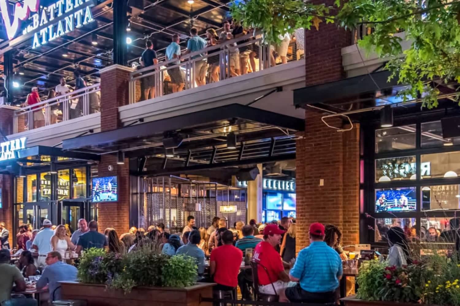 Diners on terraces and at street level outside restaurants at The Battery Atlanta in the evening.
